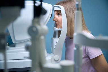 Göz sağlığı kliniğinde göz tedavisi gören bir kadın hasta. Optometri kavramı