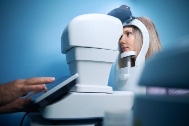 Gözlükçü kesikli lambayla görüş ölçüsü alan genç bir kadın. Tıp, sağlık hizmeti kavramı