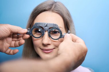 Göz muayenesi sırasında göz çerçevesi ile göz teması kuran güzel genç bir bayan. Tıp, sağlık hizmeti kavramı