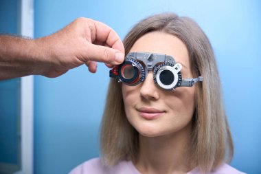 Göz muayenesi sırasında optometrist gözlük takan gülümseyen kadın hasta. Tıp, sağlık hizmeti kavramı
