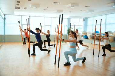 Spor kıyafetli sporcular jimnastik sopasıyla egzersiz yapıyorlar. Fitness, spor, eğitim, spor salonu ve yaşam tarzı konsepti