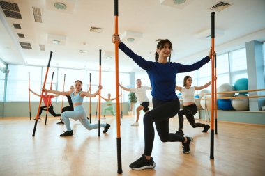 Spor salonunda jimnastik sopalarıyla denge egzersizleri yapan insanlar. Fitness, spor, eğitim, spor salonu ve yaşam tarzı konsepti