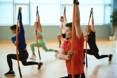Sportif insanlar spor salonunda jimnastik sopalarıyla egzersiz yapıyorlar. Fitness, spor, eğitim, spor salonu ve yaşam tarzı konsepti