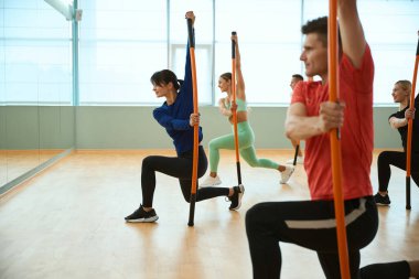 Jimnastik sopaları olan tecrübeli bir koçun rehberliğinde antrenman yapan sporcular. Fitness, spor, eğitim, spor salonu ve yaşam tarzı konsepti