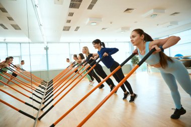 Modern spor salonunda jimnastik sopalarıyla antrenman yapan sporcular. Fitness, spor, eğitim, spor salonu ve yaşam tarzı konsepti