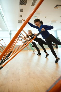 Bir grup insan jimnastik sopasıyla spor salonunda antrenman yapıyor. Fitness, spor, eğitim, spor salonu ve yaşam tarzı konsepti