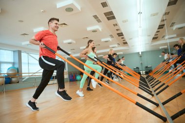 Sportif insanlar sıraya girip jimnastik sopalarıyla egzersiz yapıyorlar. Fitness, spor, eğitim, spor salonu ve yaşam tarzı konsepti
