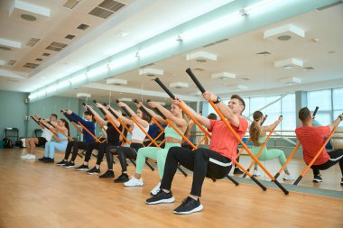 Mutlu insanlar spor salonunda jimnastik sopasıyla egzersiz yapıyorlar. Fitness, spor, eğitim, spor salonu ve yaşam tarzı konsepti