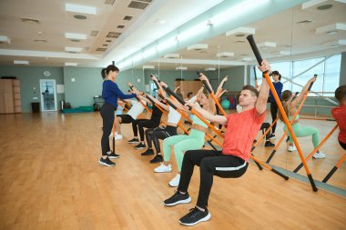 Sportif insanlar spor salonunda jimnastik çubukları kullanan bir eğitmenle ilişki kurar. Fitness, spor, eğitim, spor salonu ve yaşam tarzı konsepti