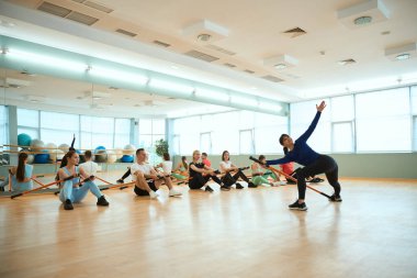Spor salonunda jimnastik çubukları kullanarak insanlara fiziksel egzersiz yaptıran kadın antrenör. Fitness, spor, eğitim, spor salonu ve yaşam tarzı konsepti
