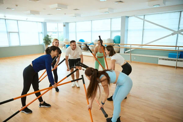 Sportif insanlar spor salonunda jimnastik sopalarıyla çalışmaya başlıyorlar. Fitness, spor, eğitim, spor salonu ve yaşam tarzı konsepti