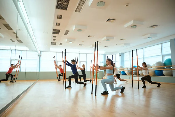 Spor salonunda spor ayakkabıları içinde spor sopalarıyla antrenman yapan grup üyeleri. Fitness, spor, eğitim, spor salonu ve yaşam tarzı konsepti
