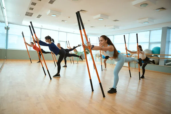 Beden eğitimi sınıfındaki insanlar jimnastik çubuklarıyla denge egzersizleri yapıyorlar. Fitness, spor, eğitim, spor salonu ve yaşam tarzı konsepti