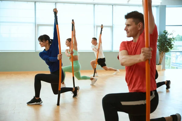 Deneyimli bir koçun rehberliğinde jimnastik sopalarıyla spor yapan bir grup insan. Fitness, spor, eğitim, spor salonu ve yaşam tarzı konsepti