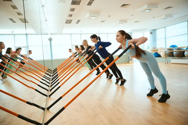 Modern spor salonunda jimnastik sopalarıyla çalışan bir grup genç. Fitness, spor, eğitim, spor salonu ve yaşam tarzı konsepti