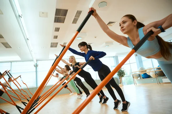 Modern spor salonunda spor sopalarıyla antrenman yapan kadınlar ve erkekler. Fitness, spor, eğitim, spor salonu ve yaşam tarzı konsepti