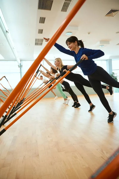 Bir grup insan jimnastik sopasıyla spor salonunda antrenman yapıyor. Fitness, spor, eğitim, spor salonu ve yaşam tarzı konsepti