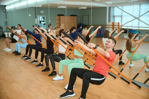Spor salonunda jimnastik sopasıyla antrenman yapan bir grup insan. Fitness, spor, eğitim, spor salonu ve yaşam tarzı konsepti