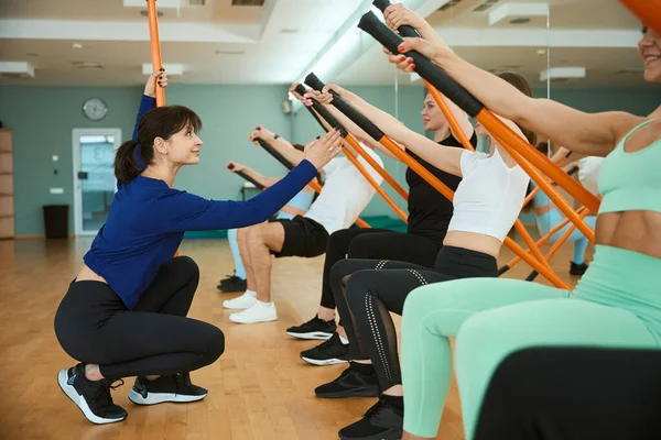 Bayan antrenör, spor salonunda jimnastik çubukları kullanarak insanların antrenmanına yardım ediyor. Fitness, spor, eğitim, spor salonu ve yaşam tarzı konsepti