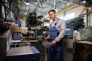 Professional production workers in coverall working with different PVC windows at factory