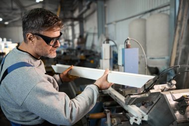 Alüminyum ve PVC pencere üretimi için fabrikada pencere montajı yapan elle çalışan işçiler