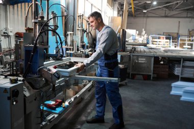 Alüminyum ve PVC pencere üretimi için fabrikada pencere montajı yapan elle çalışan işçiler