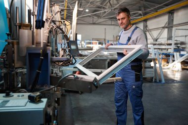 Fabrikadaki farklı PVC pencereleriyle çalışan profesyonel üretim işçileri