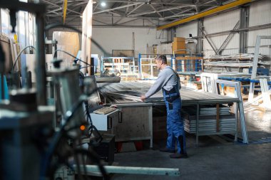 Fabrika ortamında PVC kapı ve pencere yapımında usta bir işçi.