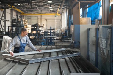 Fabrikadaki PVC kapı ve pencere montajında çalışan uzman bir erkek.