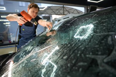 Otomatik ön camın dış yüzeyine uygulanan plazma ve ısı tabancası kullanan profesyonel bir araç.