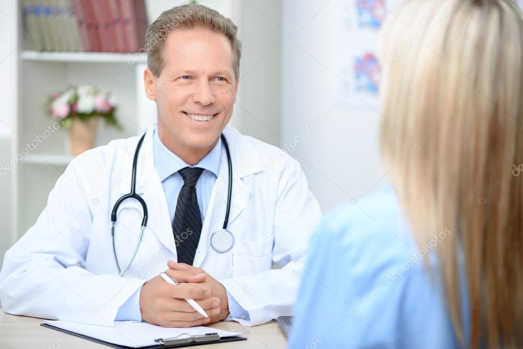 Smiling cardiologist talking to the patient