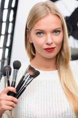 Makeup artist showing professional brushes. clipart