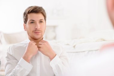 Üstüne bir gömlek koyarak sürecinde genç adam.