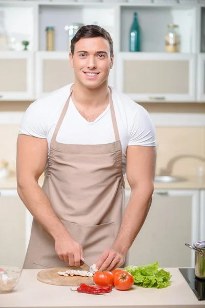 タフな男が台所で野菜を切る. — ストック写真