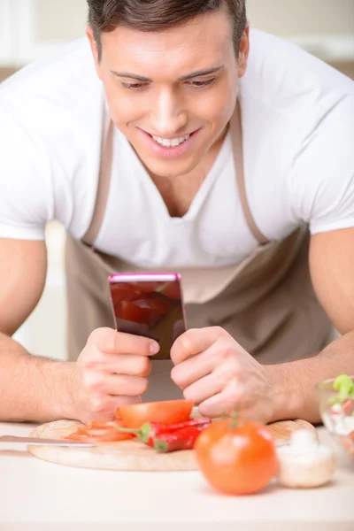 Vonzó fiatal szakács használ a smartphone. — Stock Fotó