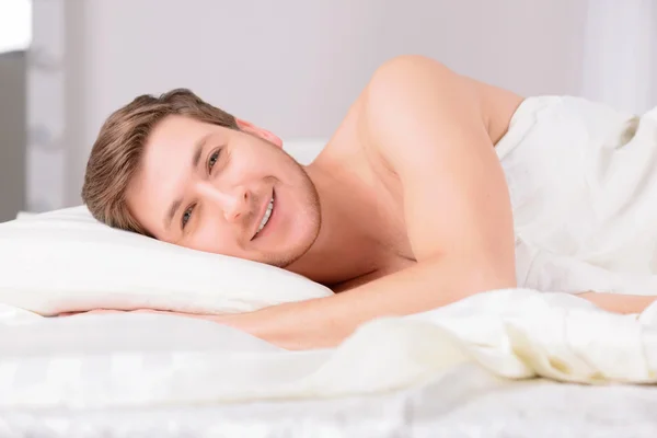 Młody człowiek w łóżku leżąc na boku. — Zdjęcie stockowe