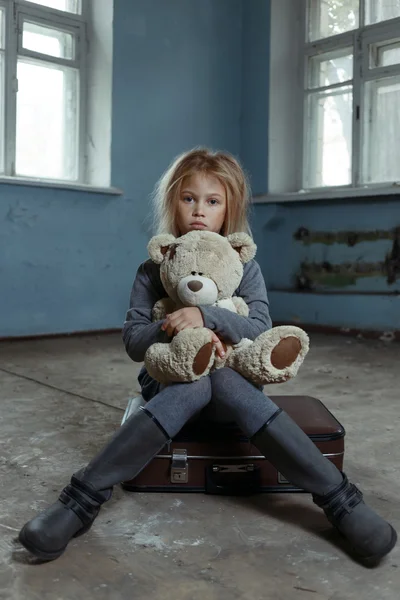 Одинокая девушка сидит на чемодане — стоковое фото