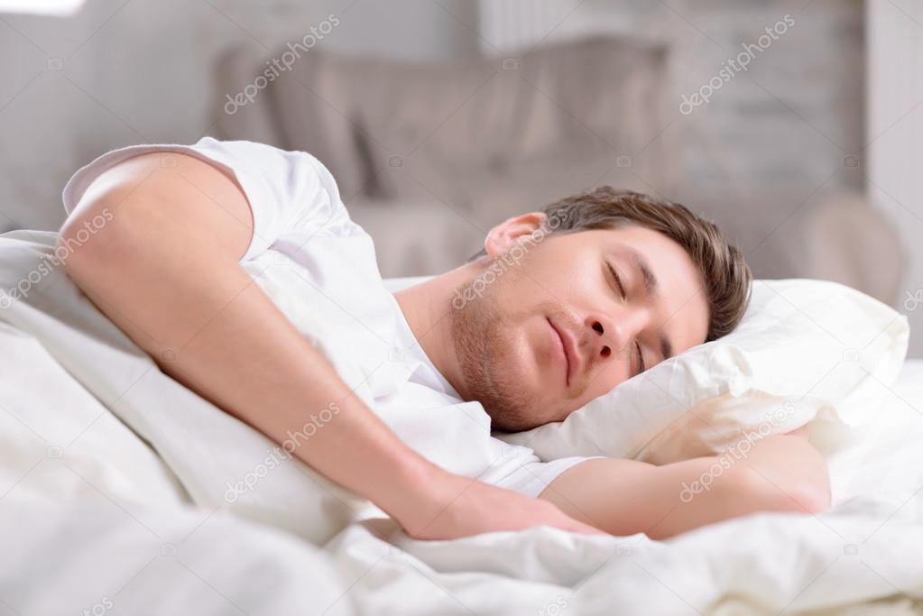 Handsome guy sleeps in his bed.