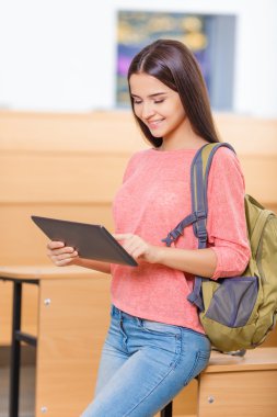 Young excellent student girl working with tablet.