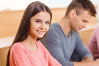 Young smiling girl is sitting at the desk.