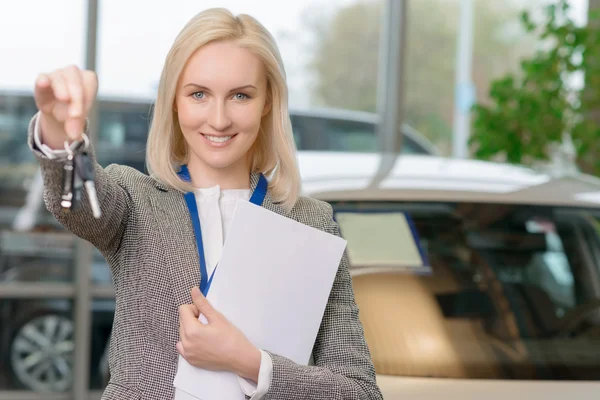 Female sales representative is upholding the car keys. — Stok fotoğraf