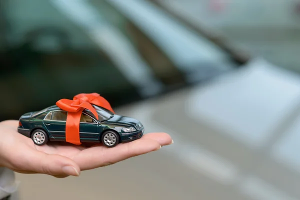 Petite voiture souvenir sur la paume de vendeuse . — Photo