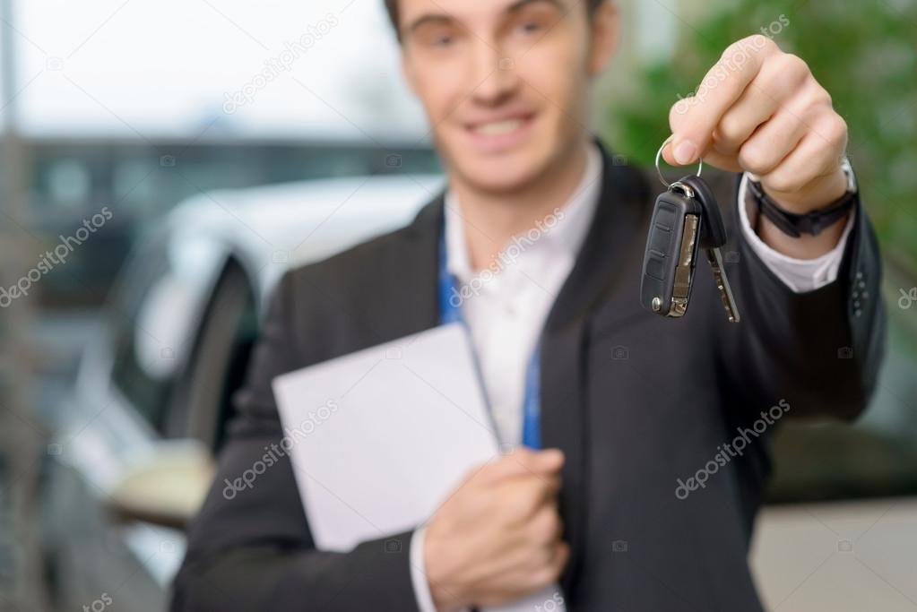Young salesman is upholding the car keys.