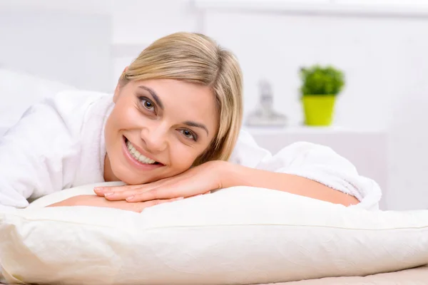 Sorrindo jovem mulher deitada na cama. — Fotografia de Stock