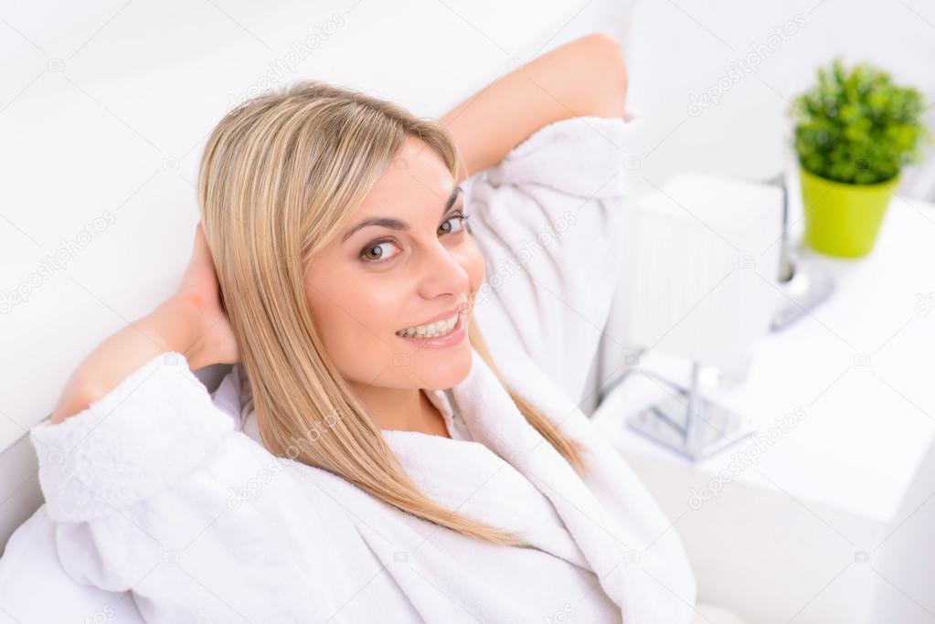 Appealing lady is smiling while resting in bed.