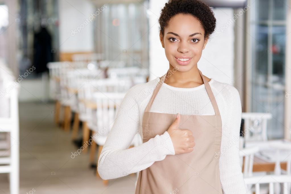 Smiling waitress showing thumbs up.