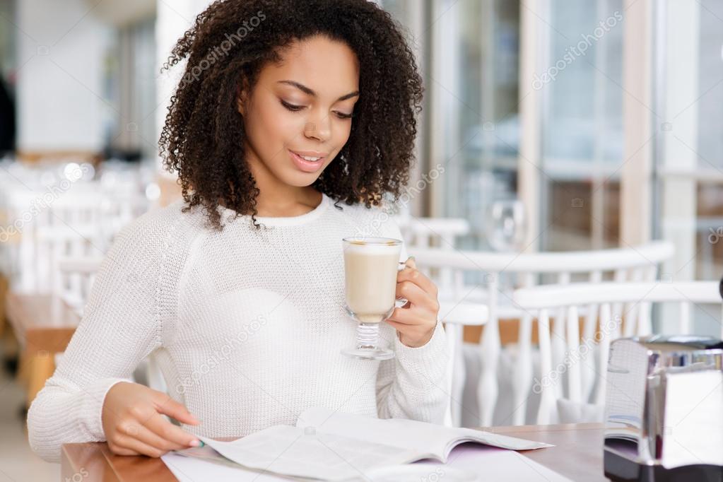 Attractive woman reading a magazine while drinking coffee.