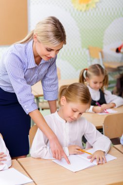 Teacher helps little girl with the task.