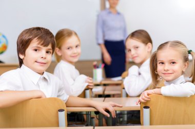 Four smiling pupils sitting at the desk.