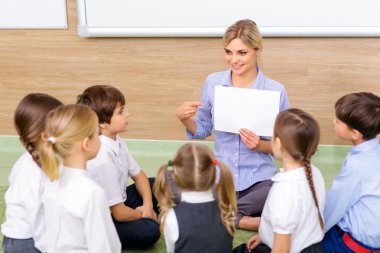 Teacher and kids are sitting in circle together. clipart